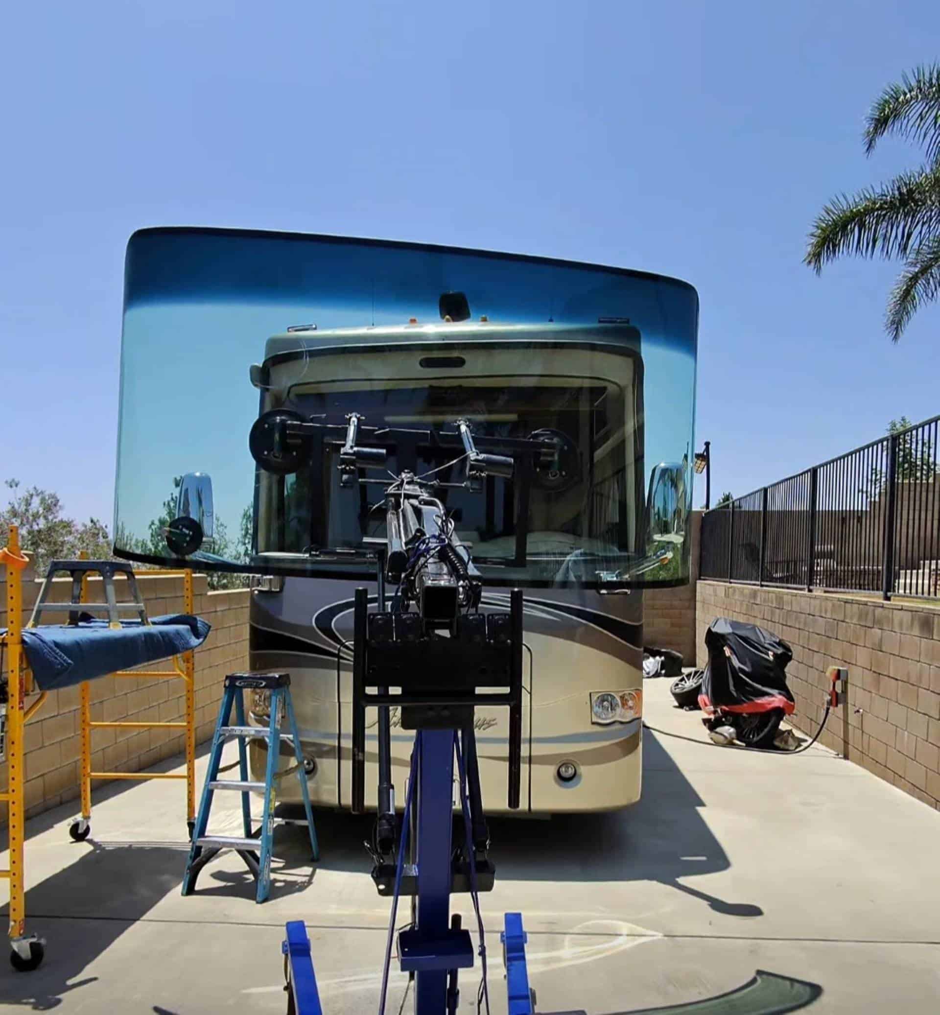 Mobile RV windshield replacement using lifting equipment in outdoor RV park setup